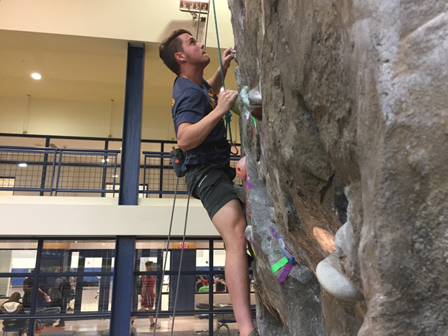 Logan Chapman climbing at the rock wall at the Student Recreation Center