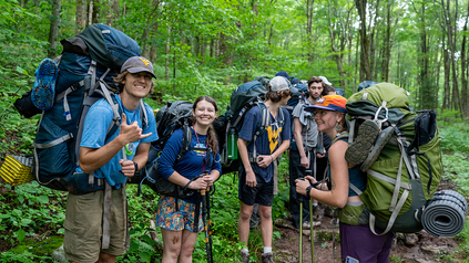 Adventure WV participants hiking in the forest and posing for a photo. 