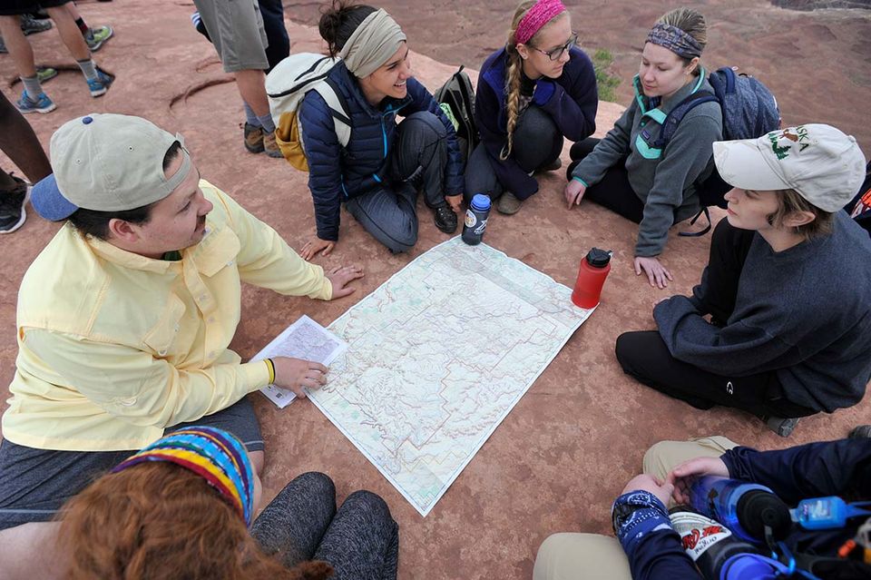 Graduate assistants sitting in a circle gathered around a map while on an Adventure WV trip.