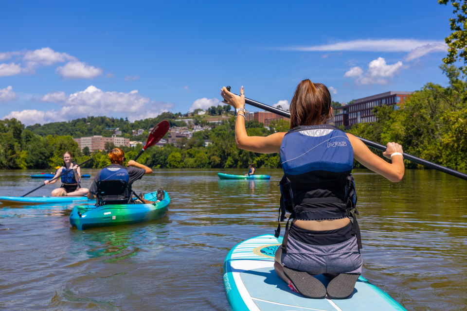 girl facing away from camera, paddle boarding on the mon river.