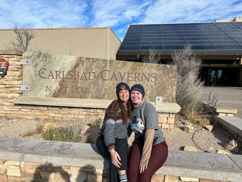 Students pose in front of a sign at Carlsbad Caverns.