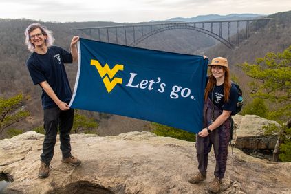 Adventure staff holding WVU flag in front of New River Gorge