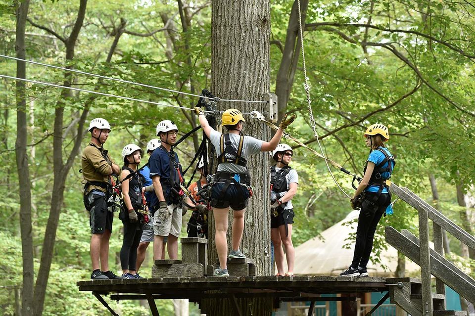 Zip-liners standing on a tree platform listening to an AdventureWV staff member give instruction.
